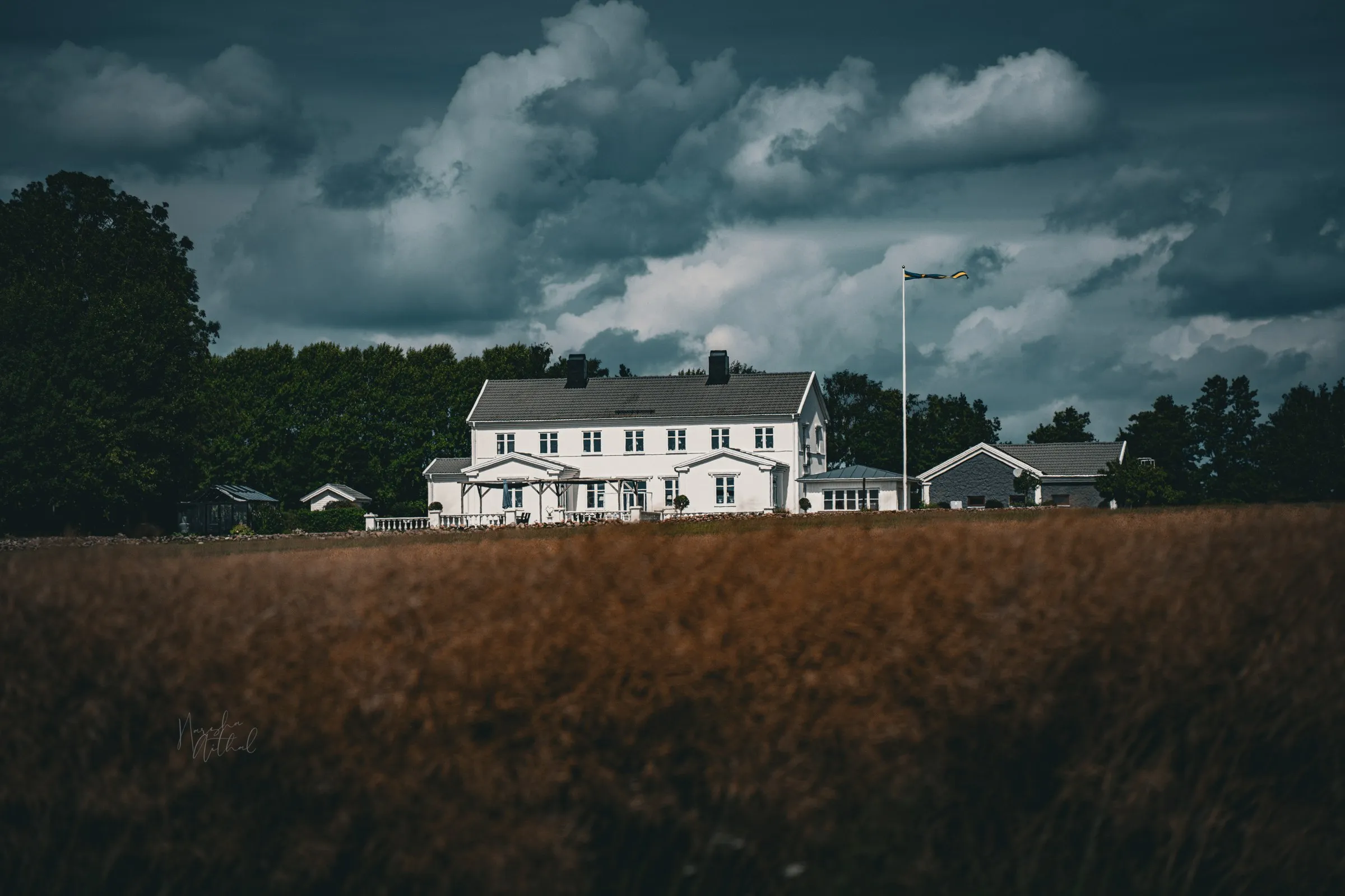 White farm buildings beneath dramatic storm clouds