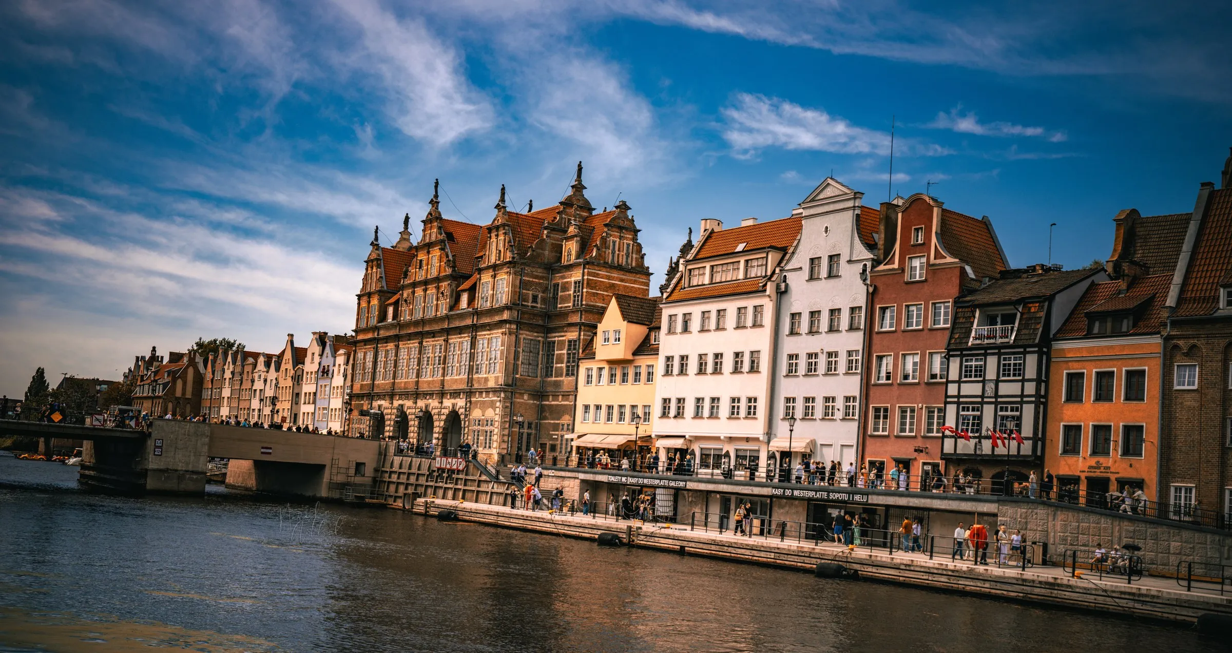 Historic riverside facades in warm sunlight under a blue sky